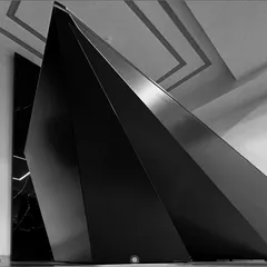 A close view of the desk's large dark planes beneath a geometric ceiling.