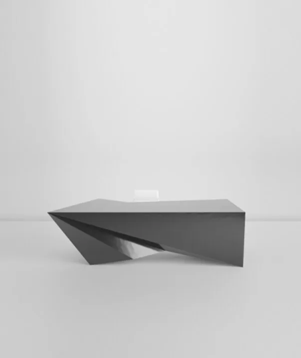A perspective rendering shows the dark angular desk isolated against a pale background.