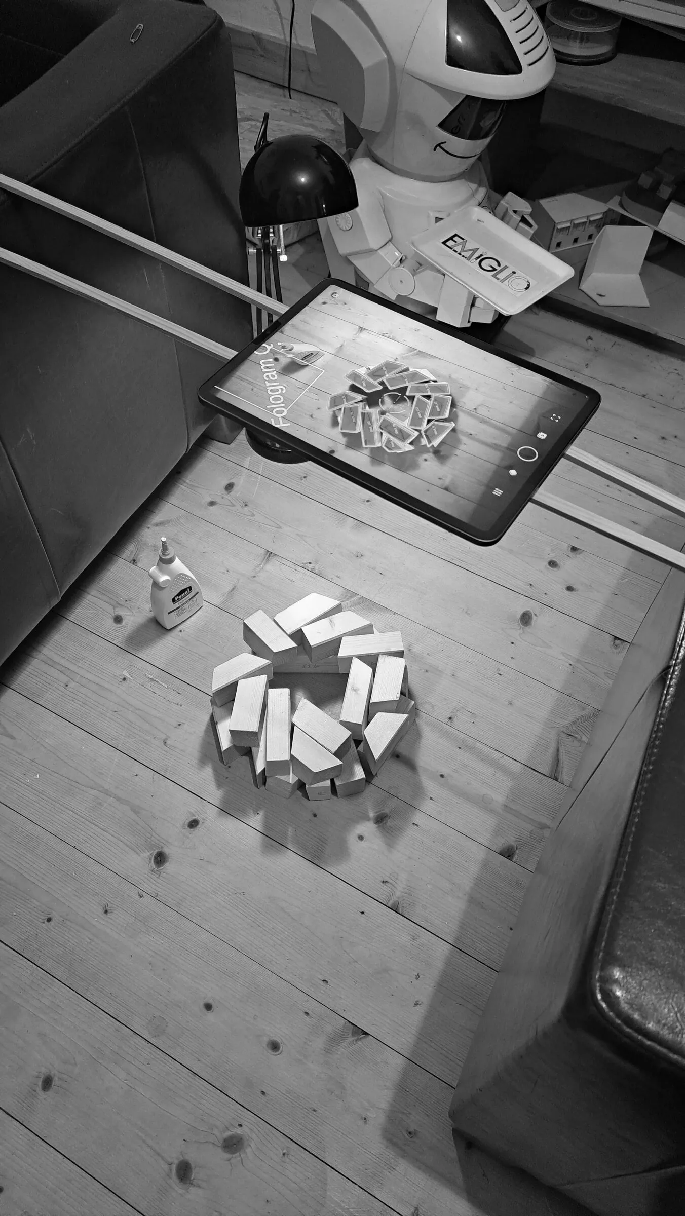 Black and white view of a tablet model above a ring of real wooden blocks.
