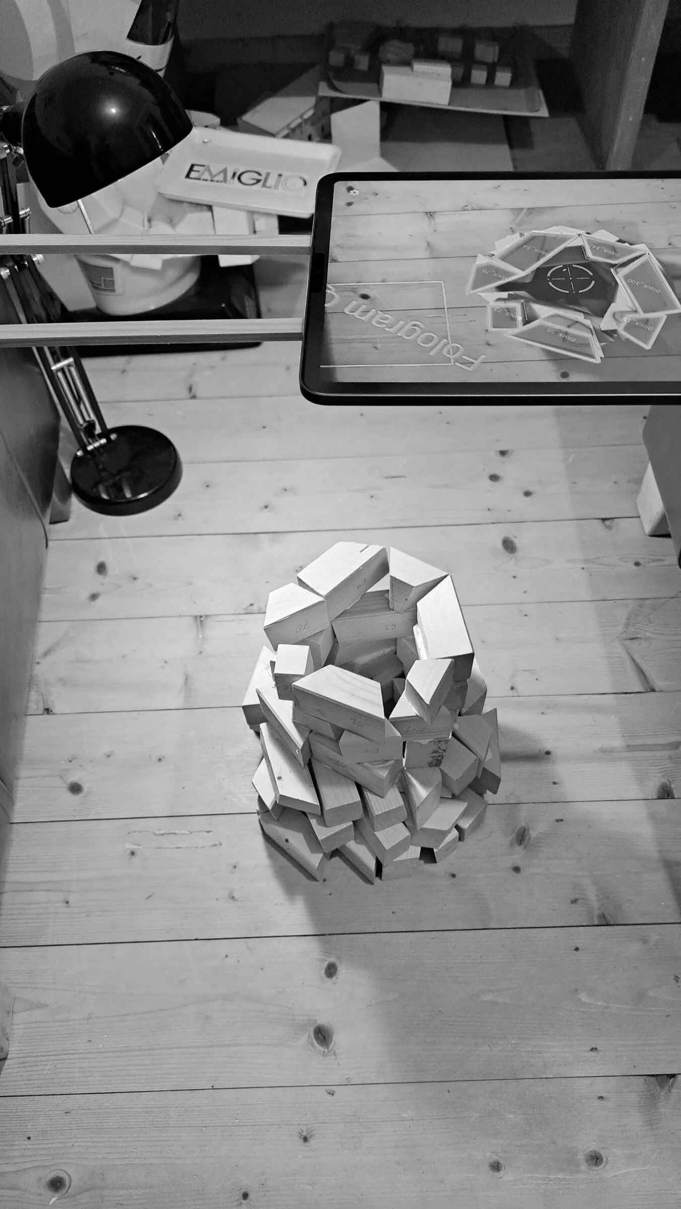 A tablet displays a block arrangement beside the matching pieces on the floor.
