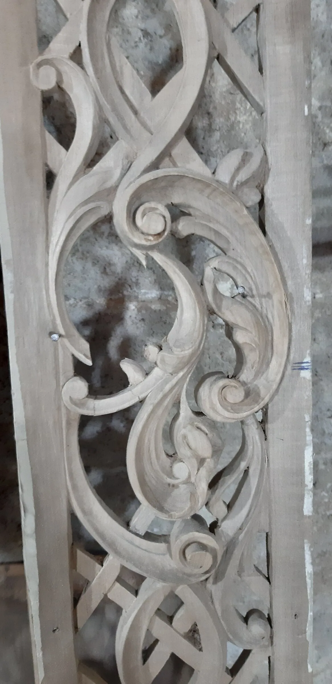Vertical carved wood panel shows deep scrolls and layered floral details.