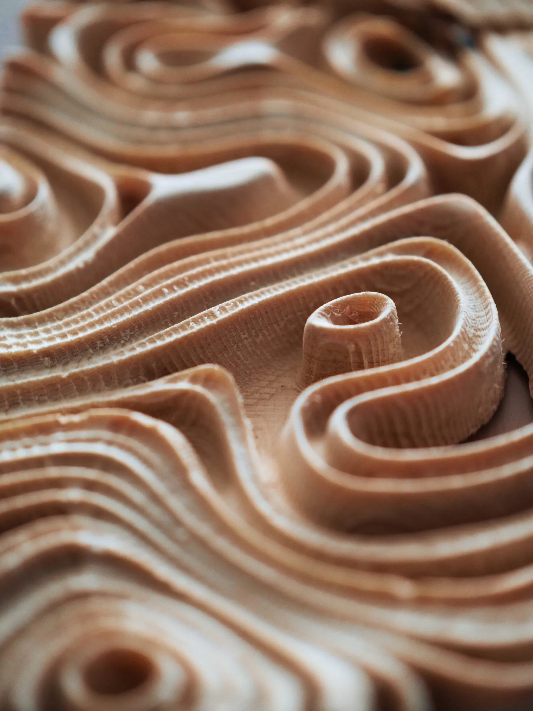 Close view of carved wood ridges that curl into rounded pockets and flowing lines.